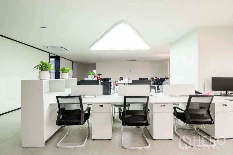 Office Space for rent or sale in Huai Khwang, Bangkok - Row of white desks under a statement triangular LED ceiling light.
