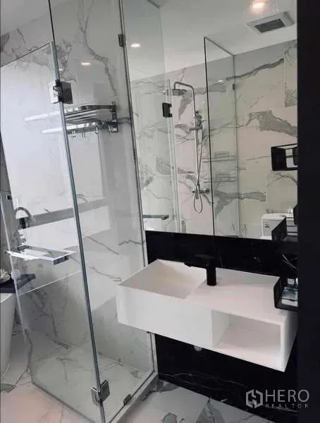Condominium for rent in Khlong Toei, Bangkok - Vanity with rectangular sink beside glass shower in luxury bathroom.