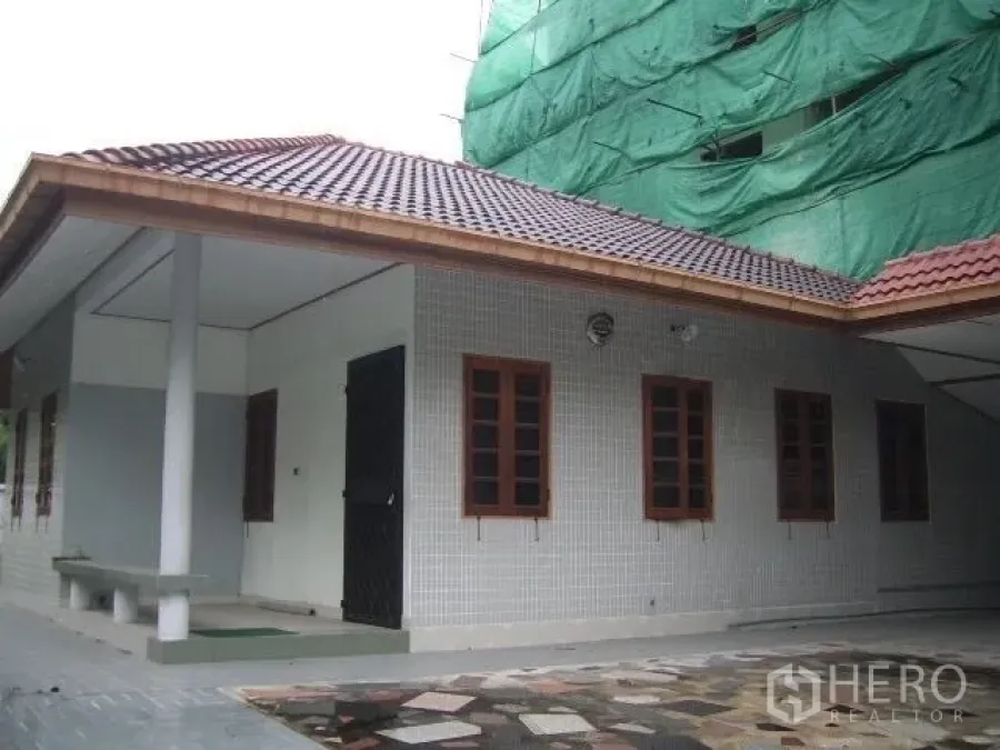 零售空间 出租在Watthana, Bangkok - 单层建筑外观，瓦屋顶、多扇木框窗与宽敞铺装前院。