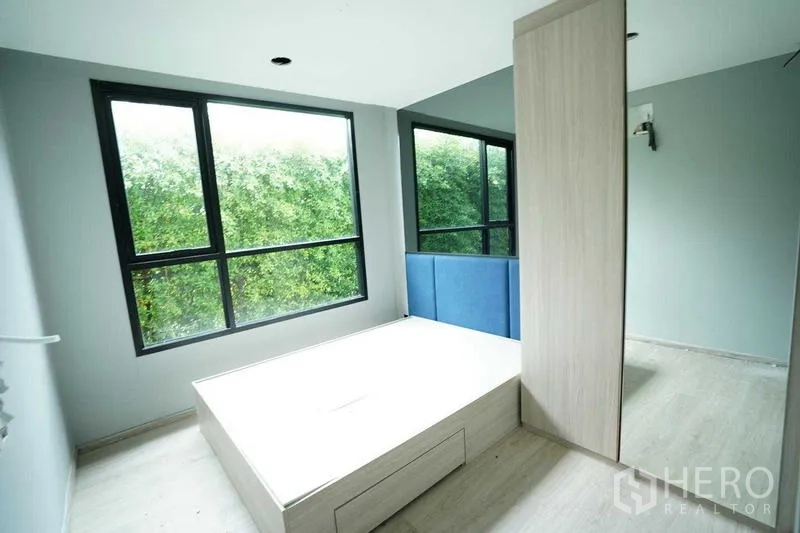 Standalone for rent in Bang Na, Bangkok - Room with corner windows and a built-in platform overlooking green hedges.