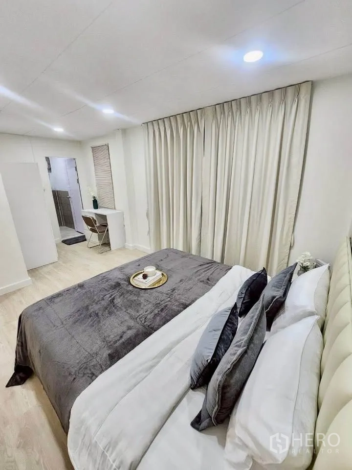 Detached House for rent in Huai Khwang, Bangkok - Bedroom with upholstered bed, desk and doorway leading to the bathroom.