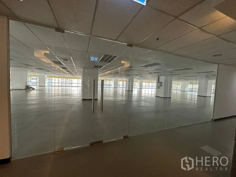 Office Space for rent - Glass double‑door entrance opening to a modern open‑plan office floor with panoramic windows.