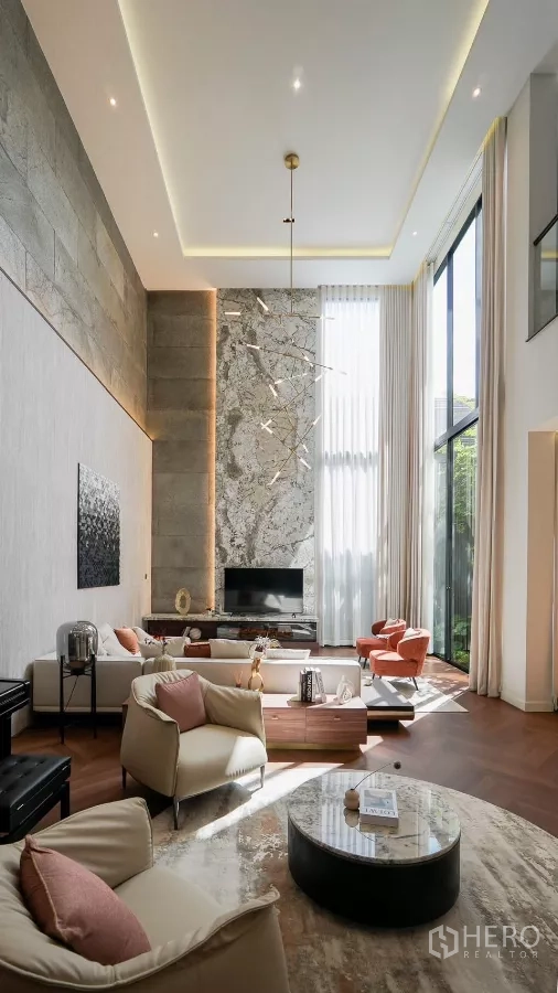 Detached House for rent or sale in Bang Kapi, Bangkok - Grand double-height lounge with statement light, stone textures and tall drapes.