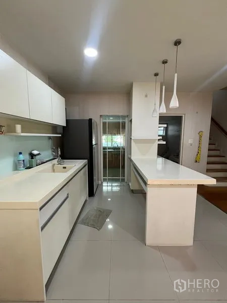 Detached House for rent in Bang Kapi, Bangkok - Pantry-style white kitchen with island, pendant lights and tall fridge.