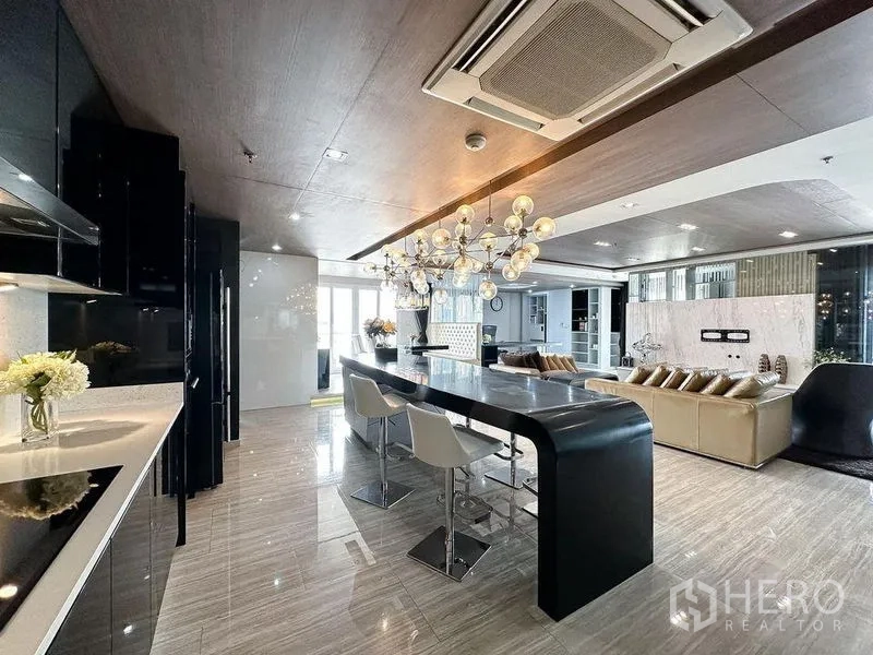Condominium for rent or sale in Khlong Toei, Bangkok - Open kitchen flowing to the living room with oversized island and polished flooring.