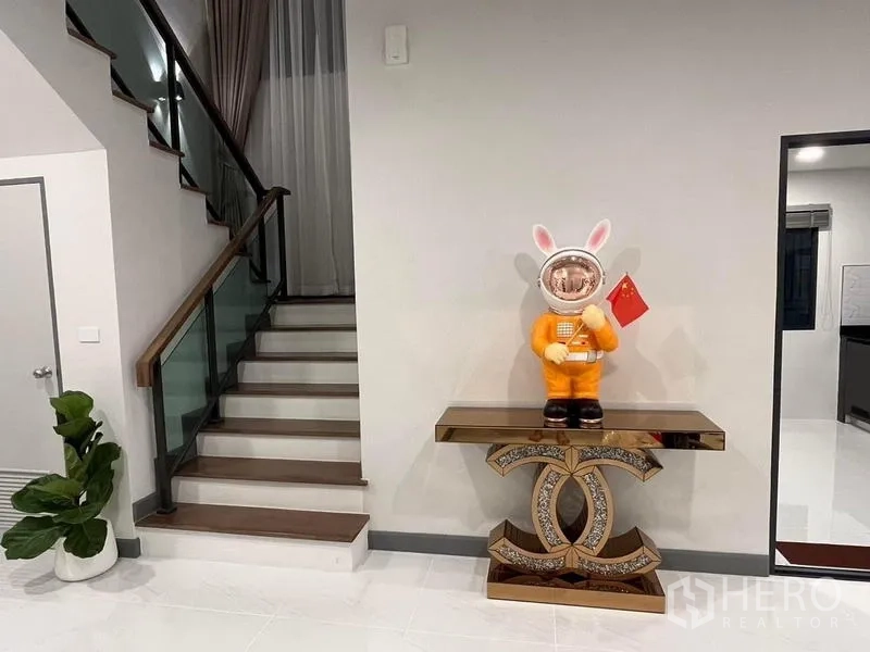 Detached House for rent - Staircase detail showing glass railing and decorative console table.