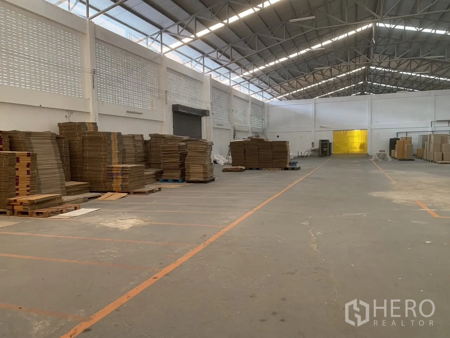 Warehouse for rent in Bang Phli, Samut Prakan - Wide warehouse floor showing roller shutter door, ventilation block walls, and pallet stacks.
