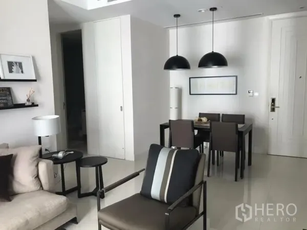 Condominium for rent in Pathum Wan, Bangkok - Four‑seat dining table under twin black pendant lamps beside the entryway.