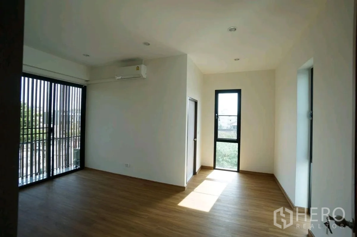 Home Office for rent in Chatuchak, Bangkok - Corner room with wood floors, balcony doors, and a tall window.