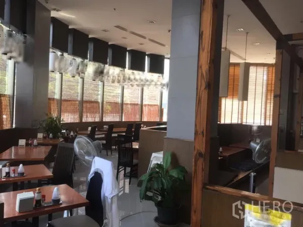 零售空间 出租在Khlong Toei, Bangkok - 店内为餐饮风格装修，木质餐桌、卡座、大窗与吊灯采光充足。