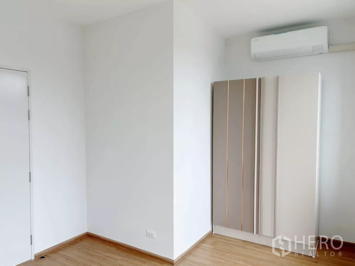Townhouse for rent in Bang Phli, Samut Prakan - Spare room corner with sliding wardrobe, white walls and air conditioner.