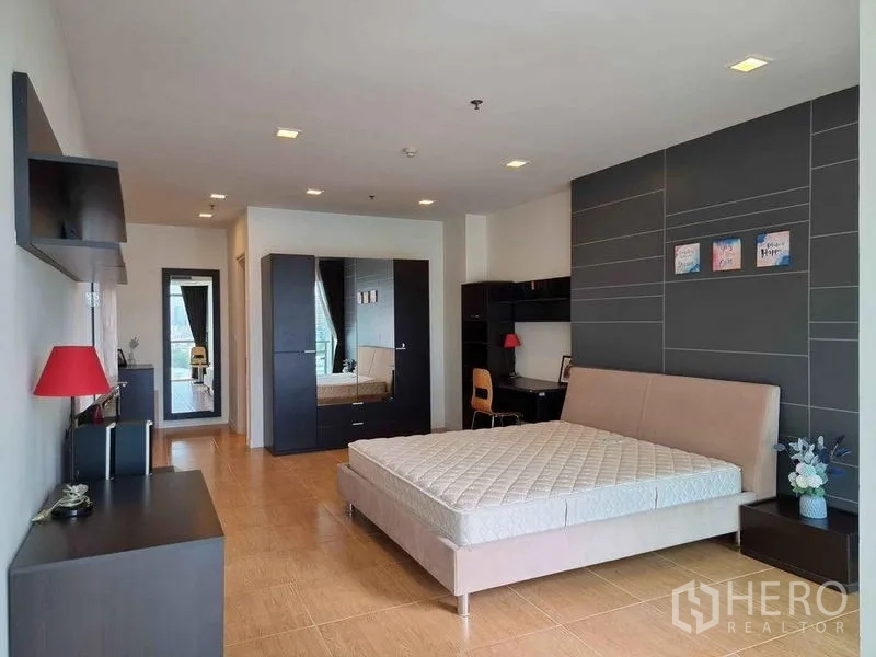 Condominium for rent in Khlong Luang, Pathum Thani - Bedroom angle showing wardrobe, study desk and grey feature wall with artwork.