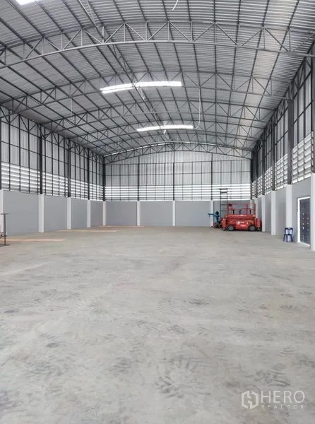 Factory for sale in Mueang Samut Sakhon, Samut Sakhon - High-clear warehouse interior with steel truss roof, concrete floor and strip ventilation.