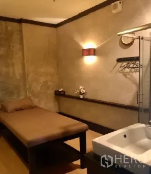 Retail Space for rent in Pathum Wan, Bangkok - Warmly lit interior room with massage bed, wall sconce lighting and a built-in sink, suitable for spa, clinic or salon use.
