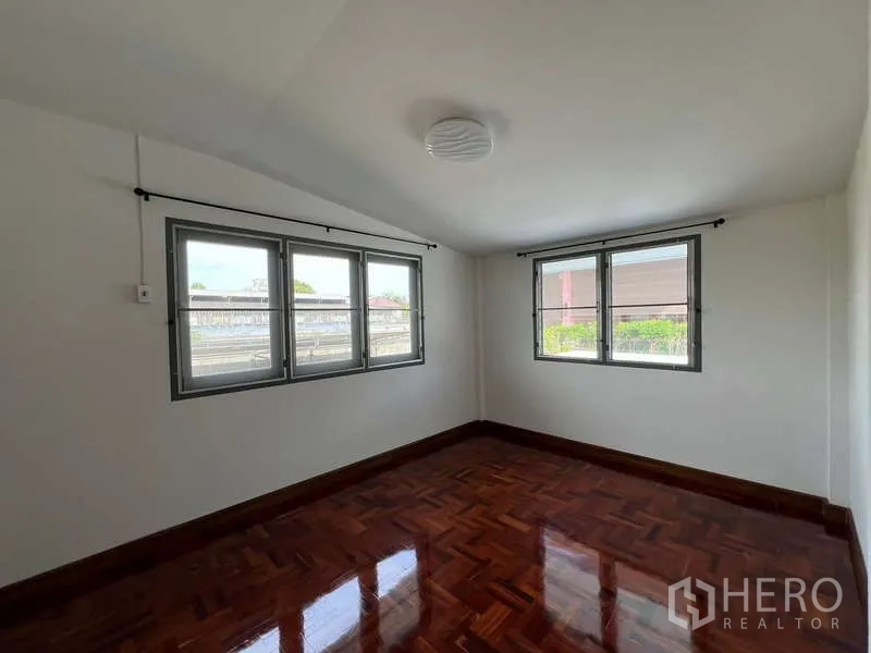 Detached House for rent in Bang Na, Bangkok - Bright upper bedroom with multiple windows and polished wooden floor.