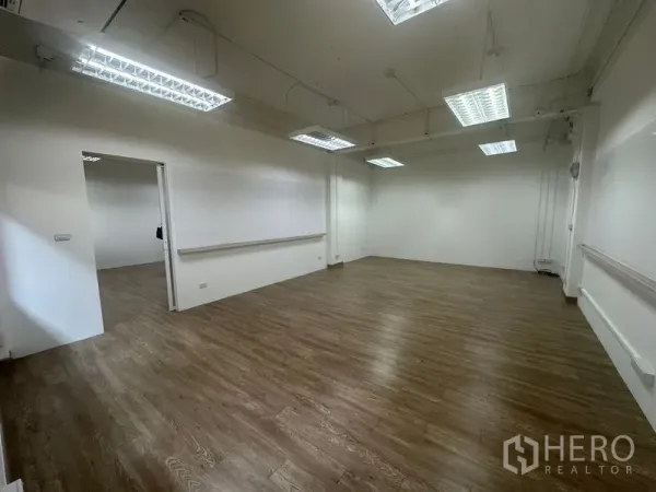 Office Space for rent in Chatuchak, Bangkok - Spacious corner office with suspended fluorescent lights, cable trunking and a sliding door to an adjacent room.