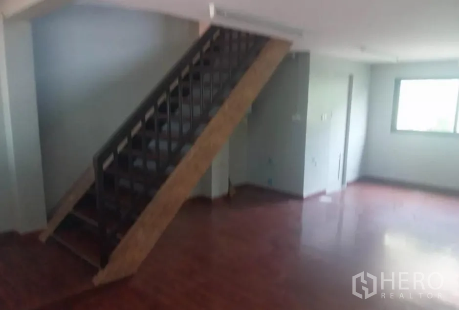 Retail Space for rent - Open area with staircase to a mezzanine level and a window, suitable for storage.