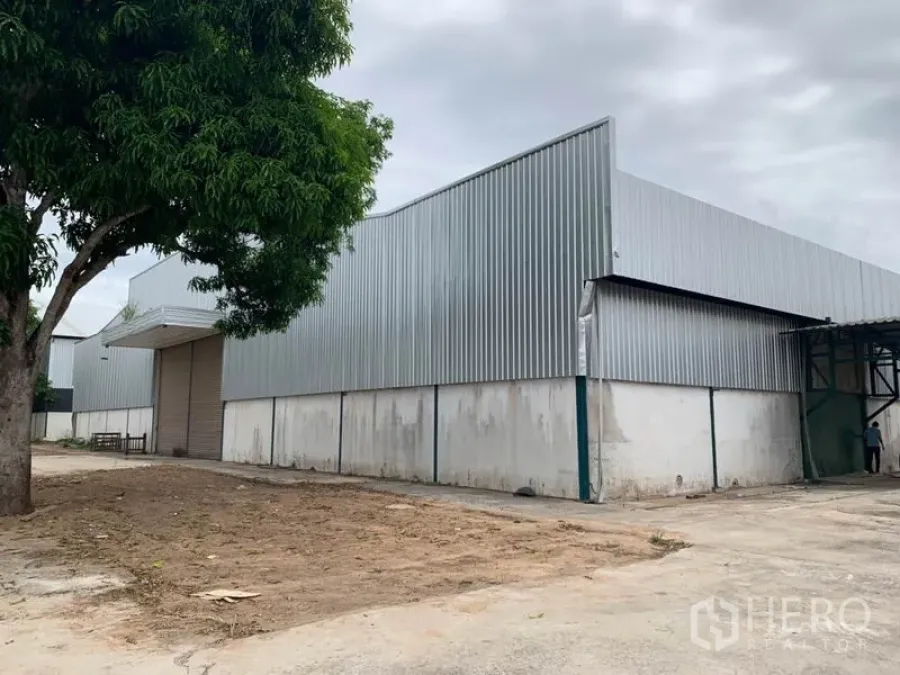 Factory for rent in Chon Buri - Steel-clad factory exterior with roll-up loading door and concrete yard in Phanat Nikhom.