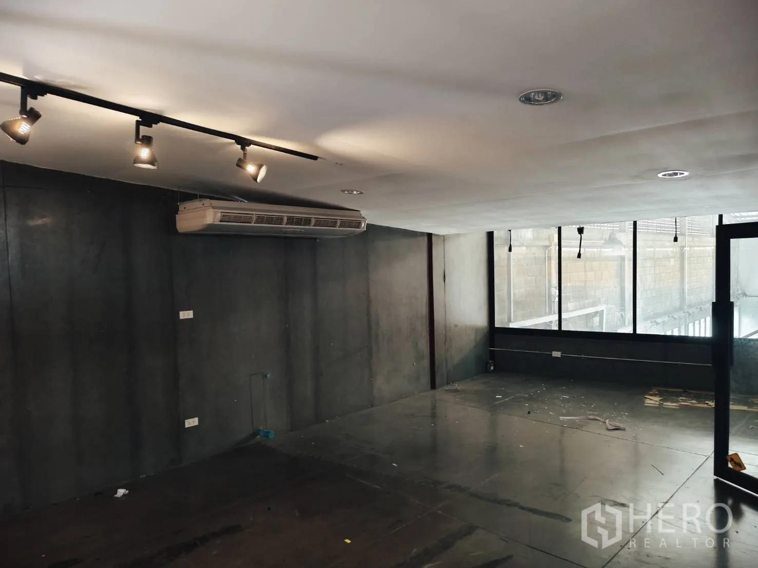 Warehouse for rent in Khlong Toei, Bangkok - Air-conditioned office room with track lighting and dark concrete walls.