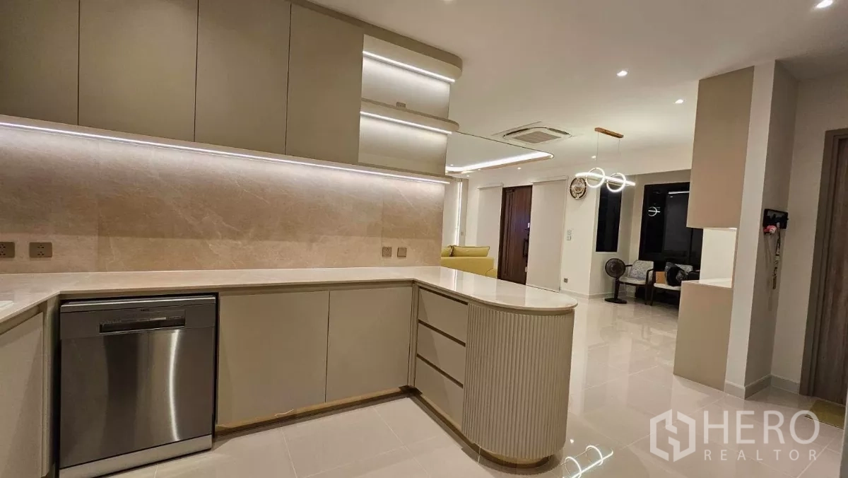 Detached House for rent or sale in Prawet, Bangkok - Kitchen worktop with integrated dishwasher, under-cabinet lighting and an island facing the seating area.
