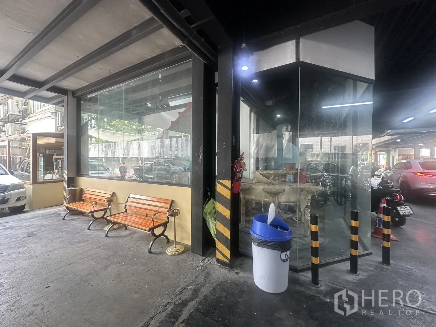 Retail Space for rent in Watthana, Bangkok - Corner glass-front retail unit under a covered area with benches and nearby driveway.