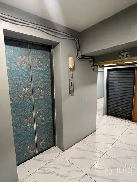 Retail Space for rent in Khlong Toei, Bangkok - Lift lobby with patterned elevator doors, tiled floors and a nearby roller shutter.