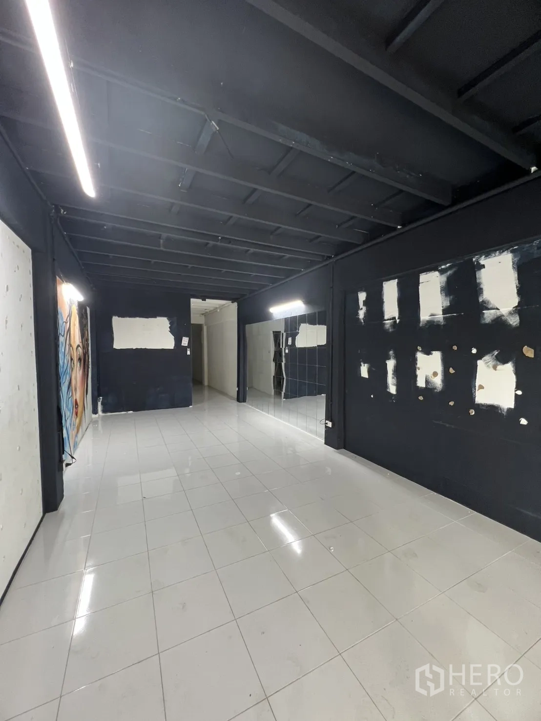Shophouse for rent or sale in Khlong Toei, Bangkok - Ground-floor retail space with black ceiling, white tiled floor and linear LED lighting.