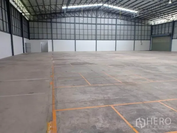 Warehouse for rent in Lat Krabang, Bangkok - Open storage floor with marked pallet bays beneath a high-clear roof and bright lighting.