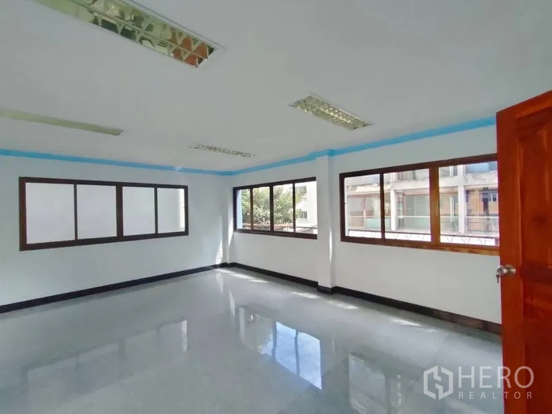 Home Office for rent in Pathum Wan, Bangkok - Corner office space with multiple windows and fluorescent ceiling lights.