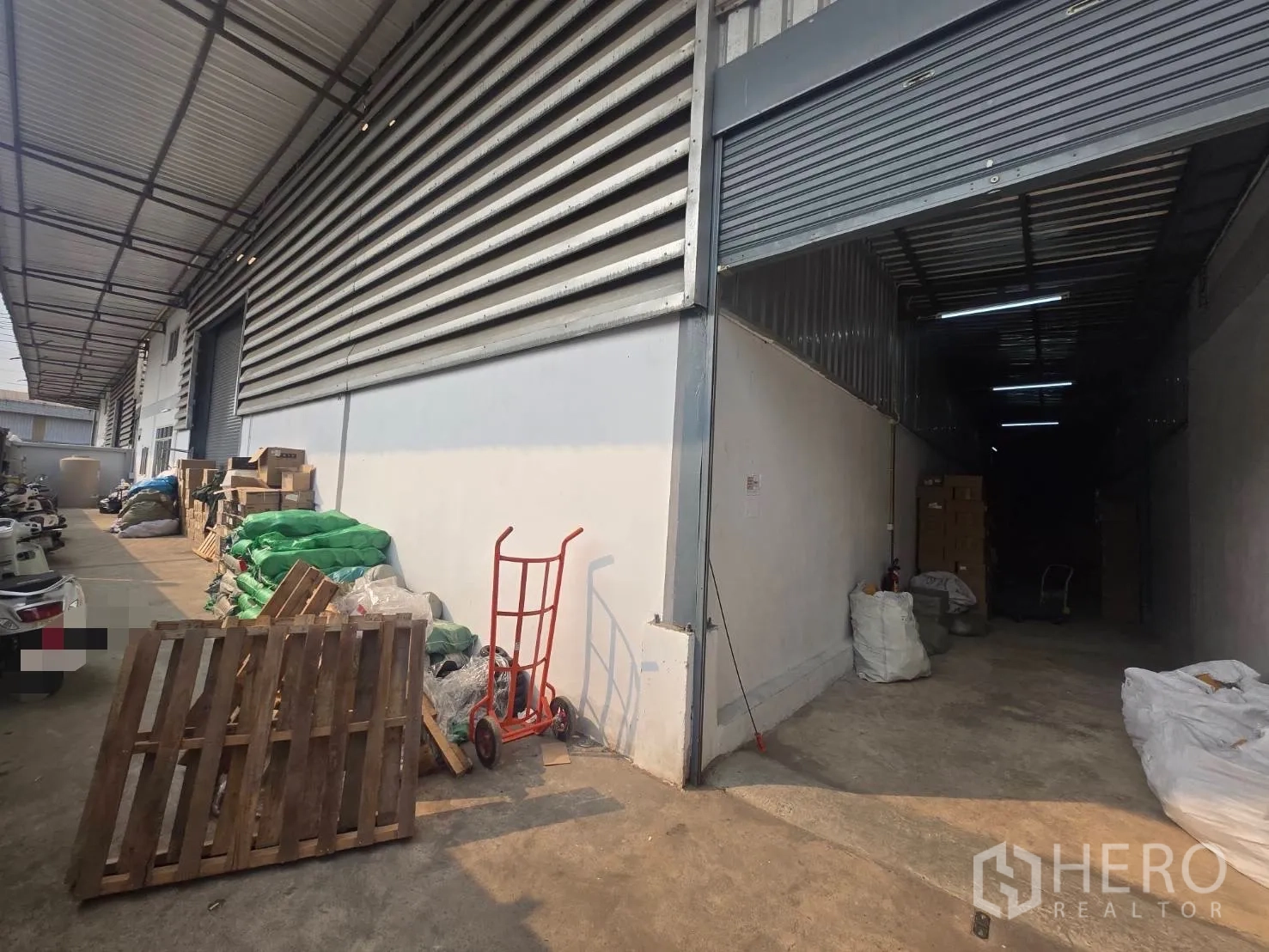 Factory for rent or sale in Mueang Samut Sakhon, Samut Sakhon - Covered loading area with open roller shutter leading to a deep storage bay.