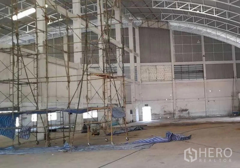 Factory for rent in Mueang Samut Prakan, Samut Prakan - Central scaffolding inside a vast warehouse with ventilation panels and high ceilings.
