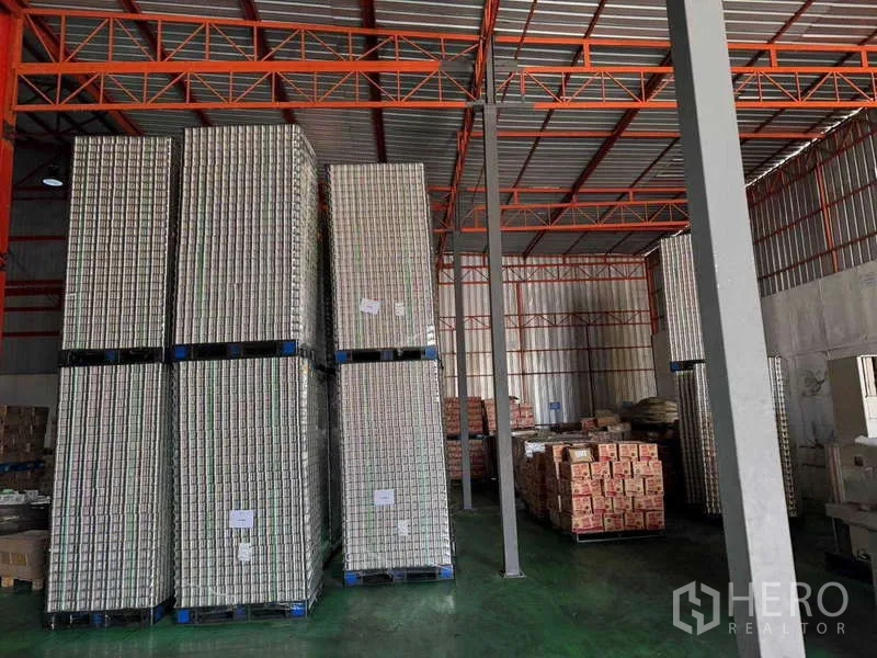 Factory for sale in Samut Prakan - Tall pallets of empty cans neatly stacked inside a storage hall.