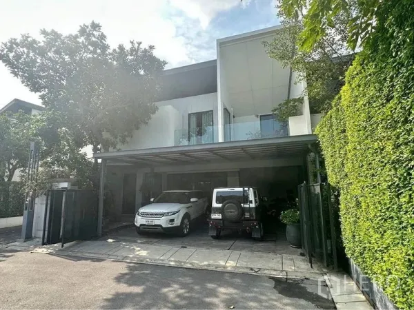 Townhouse for rent or sale in Bang Phli, Samut Prakan - Contemporary two-storey townhouse facade with wide carport, glass balcony and tall privacy hedge in Bang Phli.
