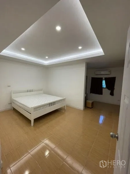 Townhouse for rent in Phra Khanong, Bangkok - Spacious bedroom with tray ceiling lighting, tiled floor and air conditioner.