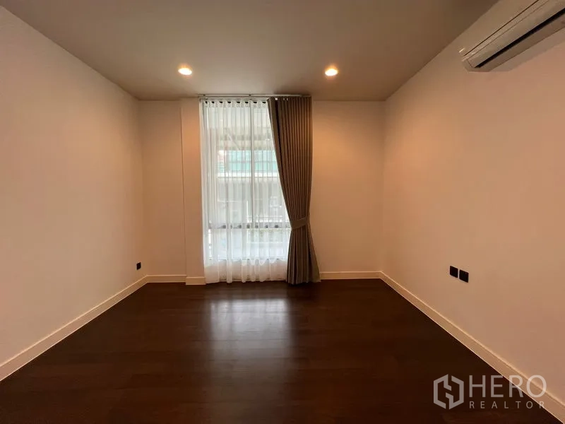 Detached House for rent in Bang Kapi, Bangkok - Ground-floor bedroom with curtains and wall-mounted air conditioner.