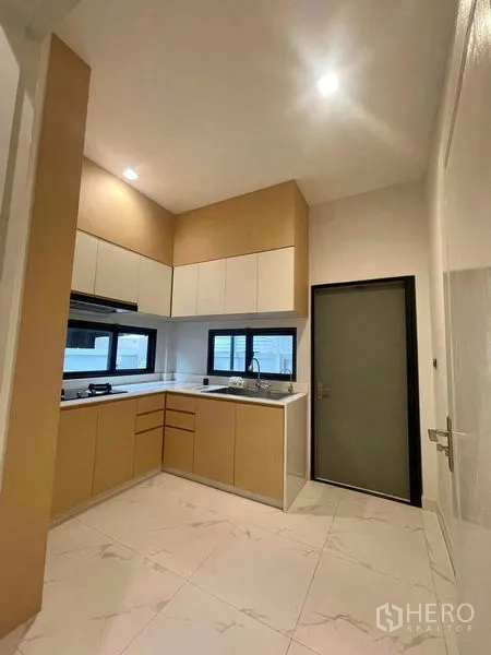 Detached House for sale in Bang Kruai, Nonthaburi - Fitted L‑shaped kitchen with upper and lower cabinets, window over the sink, stovetop and hood.
