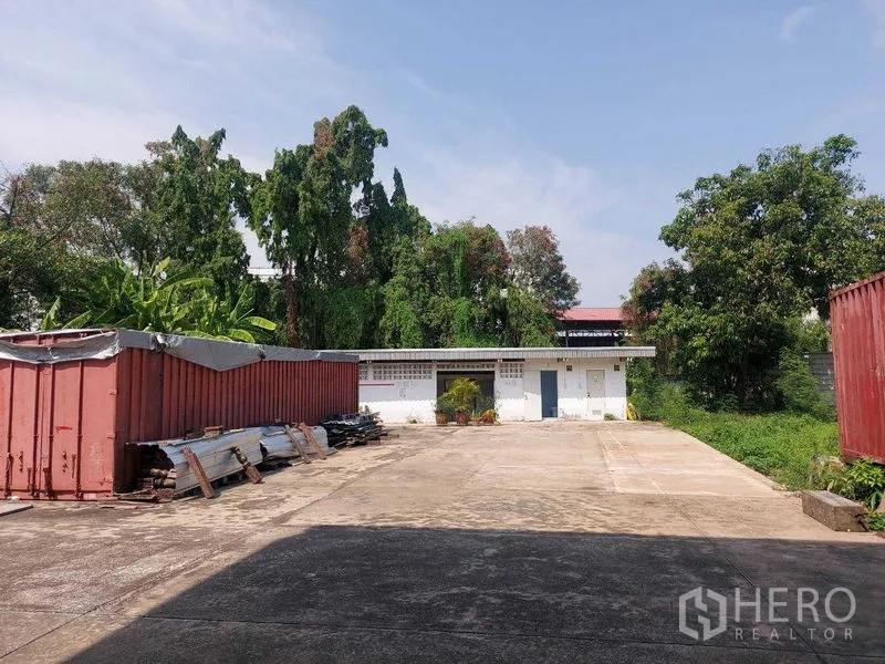 货栈 出租在Min Buri, Bangkok - 开放式堆场，混凝土硬化地面，两侧集装箱与绿化树木