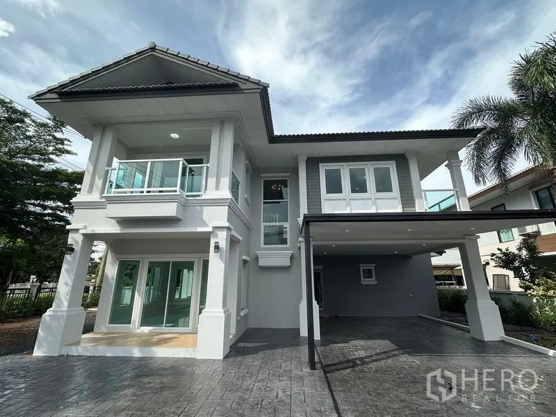 Detached House for sale in Lam Luk Ka, Pathum Thani - Two-storey detached house front facade with balconies, wide driveway and covered carport.