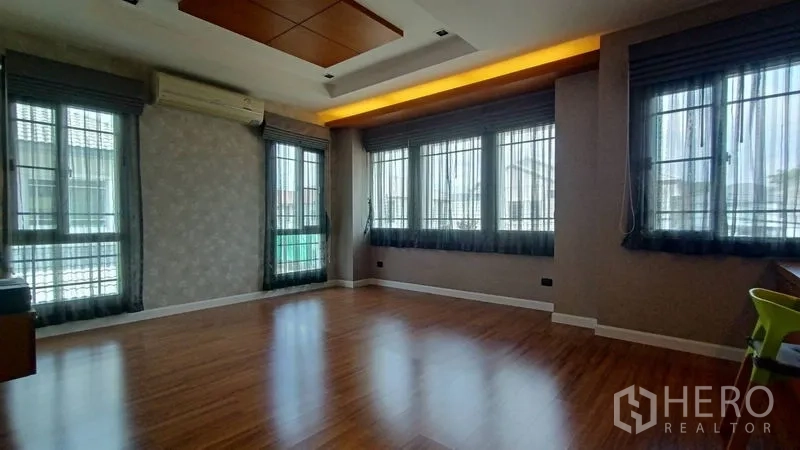 Detached House for sale in Prawet, Bangkok - Large corner bedroom with many windows, wood floors and recessed ceiling lighting.