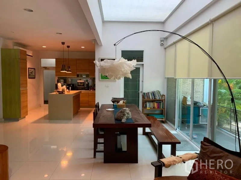 独立式住宅 出售在Suan Luang, Bangkok - 明亮的开放式餐厨区，天窗采光，长木桌、中岛台与落地窗。
