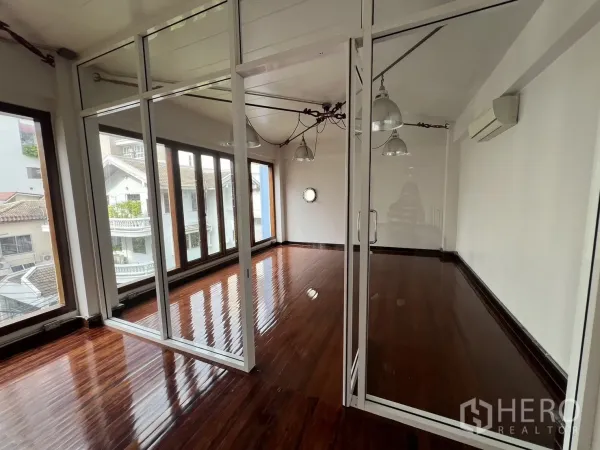 Home Office for rent in Watthana, Bangkok - Glass-partitioned meeting room with floor-to-ceiling windows and glossy wooden floors inside the home office.