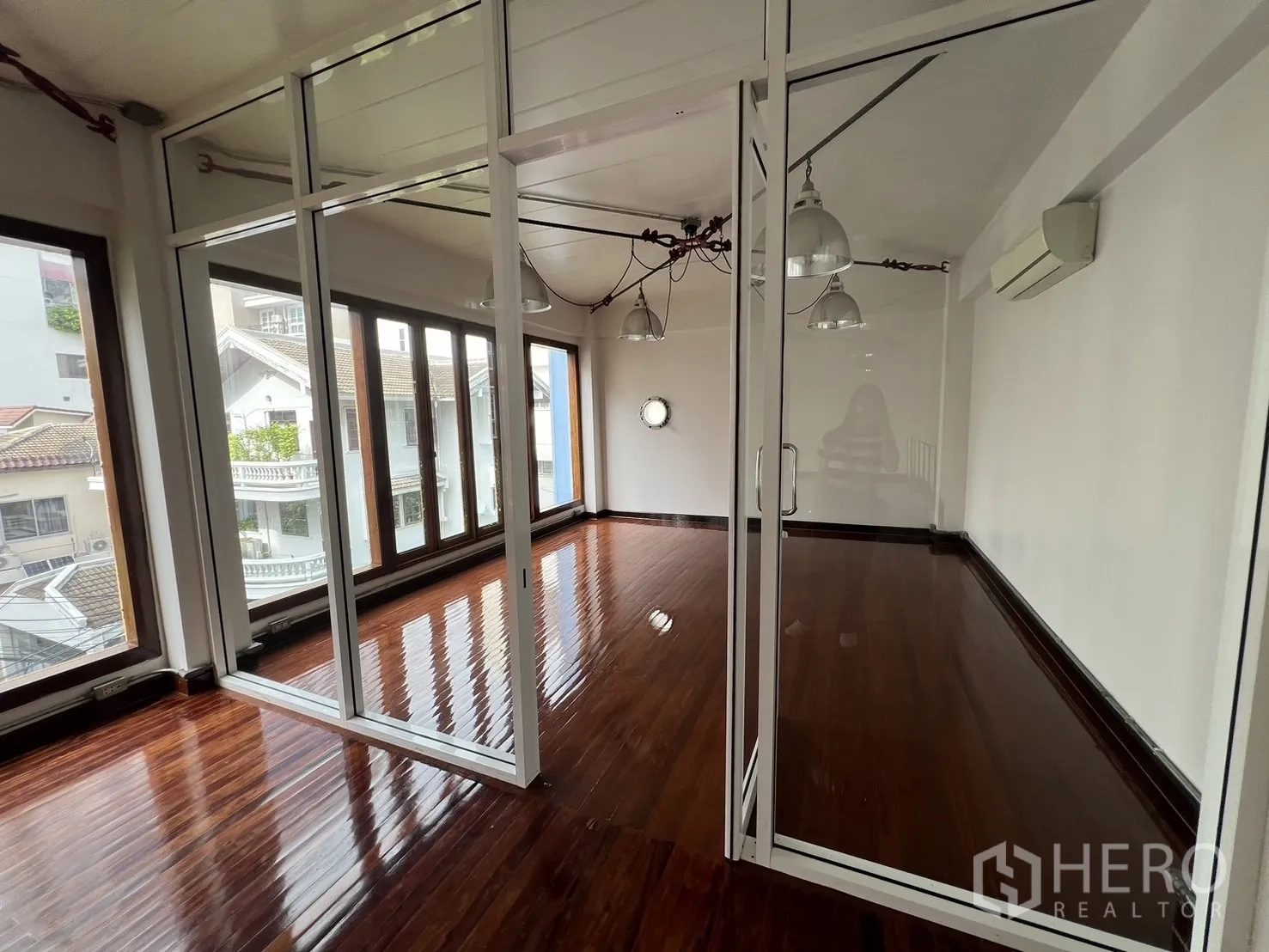 Home Office for rent in Watthana, Bangkok - Glass-partitioned meeting room with floor-to-ceiling windows and glossy wooden floors inside the home office.