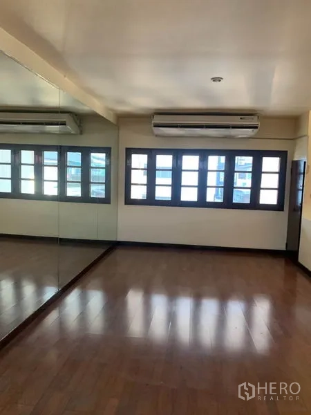 Townhouse for rent or sale in Phra Khanong, Bangkok - Sunlit room with a mirrored wall, multiple pane windows and an air conditioner.