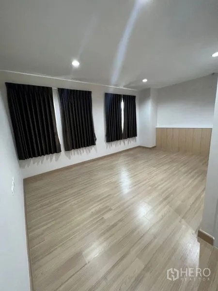 Home Office for rent - Bright office room with laminate flooring and three windows dressed with dark blackout curtains.