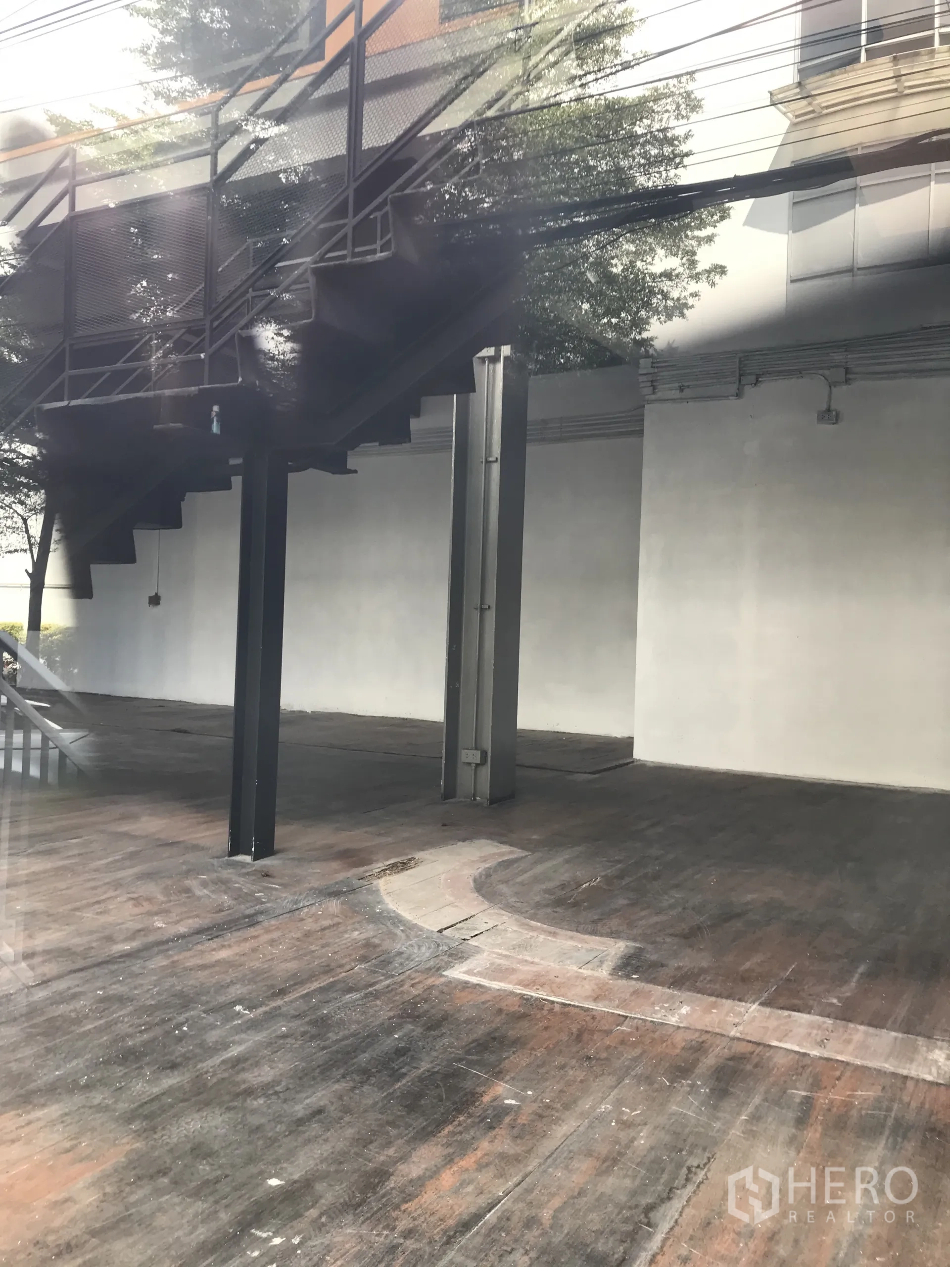 Retail Space for rent in Watthana, Bangkok - Spacious shop floor with industrial-style metal stairs above and distressed wood floorboards.