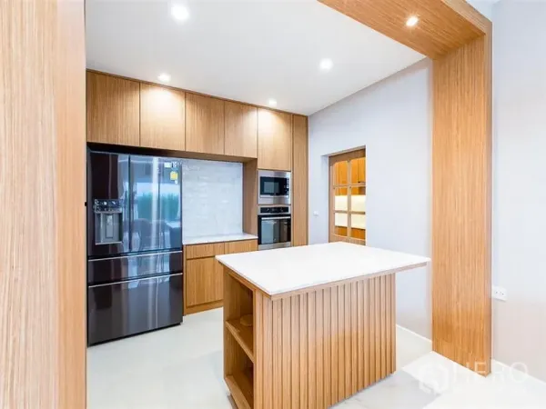 Detached House for rent or sale in Prawet, Bangkok - Modern kitchen with wood cabinetry, a central island and a double-door fridge.