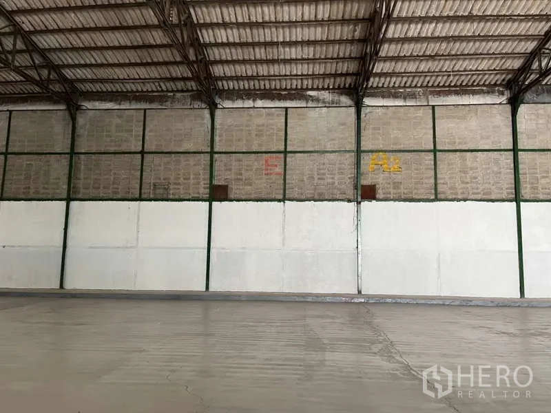 Factory for rent in Bang Pakong, Chachoengsao - Close-up of interior wall sections with steel framing and half-height white panels inside the factory.