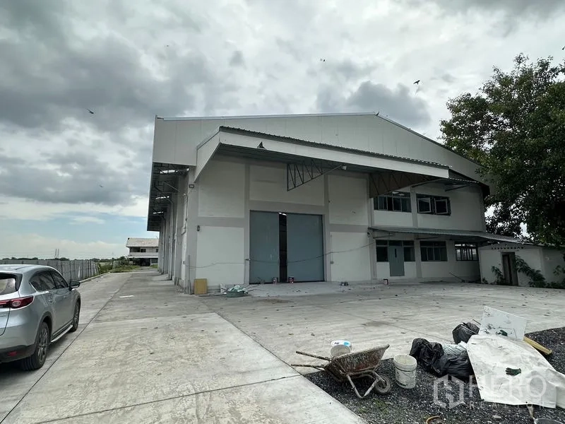 Factory for rent in Lam Luk Ka, Pathum Thani - Front facade of the factory with covered loading area, parking and access driveway.
