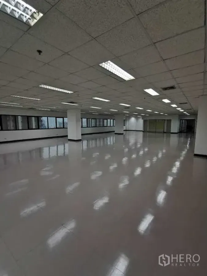 Office Space for rent in Watthana, Bangkok - Wide office floorplate with pillars, ceiling lights, and windows facing the city.