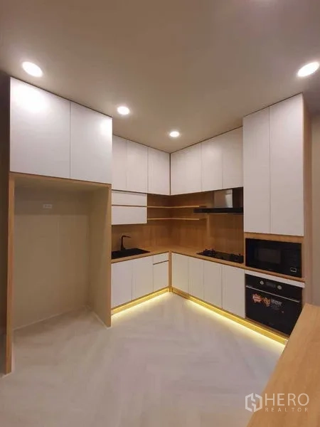 Detached House for sale in Prawet, Bangkok - L-shaped modern kitchen with white cabinetry and under-cabinet lighting.
